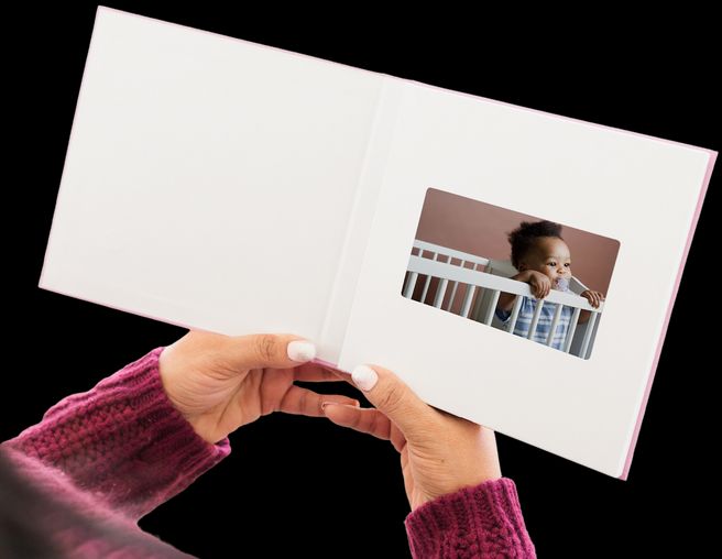 Hands holding a video book with a baby on the screen